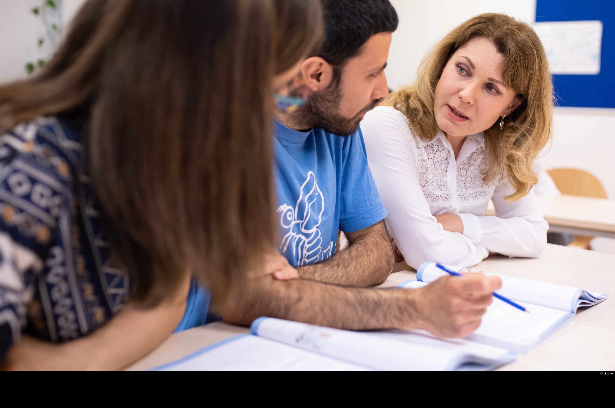 Eine Lehrerin unterrichtet im Rahmen eines Integrationskurses Migranten.